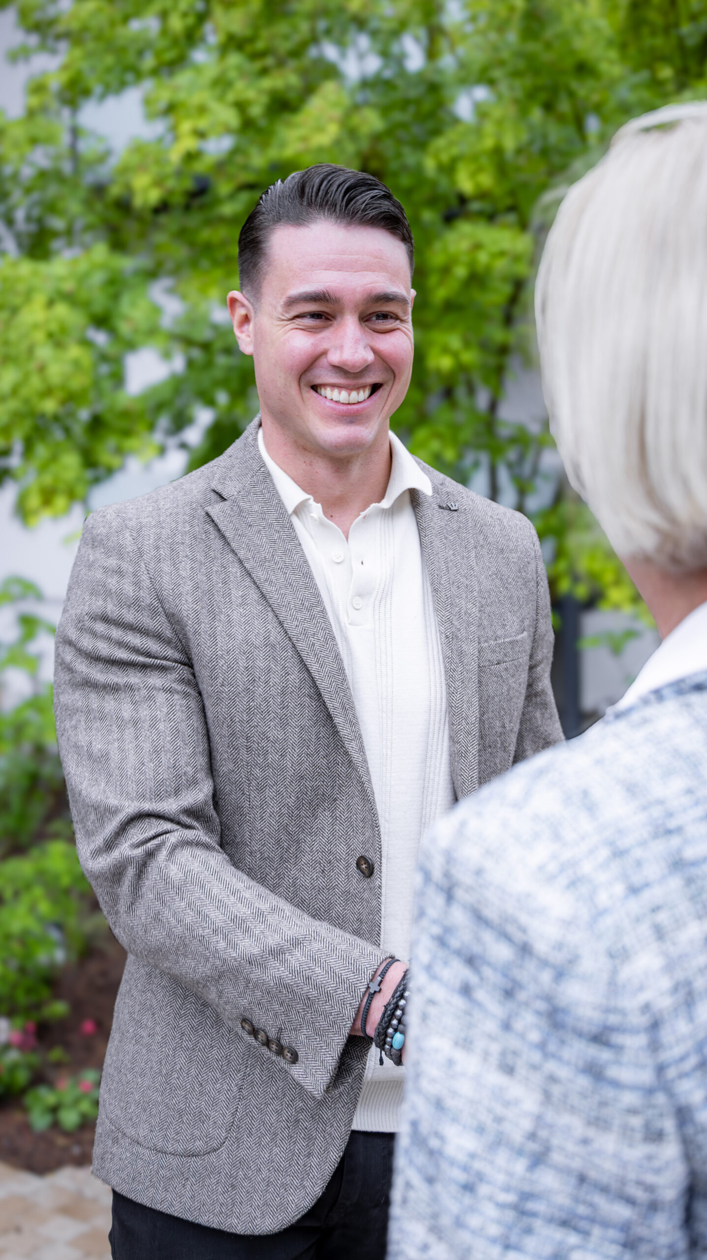 Immobilienmakler gibt Kundin die Hand und Lächelt